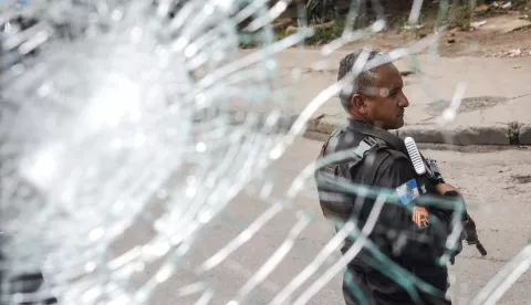 epaselect epa11813572 A police officer holds his weapon as seen through a broken window during a police operation in Rio de Janeiro, Brazil, 08 January 2025. Several people were killed during a police operation in a group of favelas in Rio de Janeiro that also targeted the facilities of the Oswaldo Cruz Foundation (Fiocruz), the main scientific research center in Brazil. EPA/ANDRE COELHO