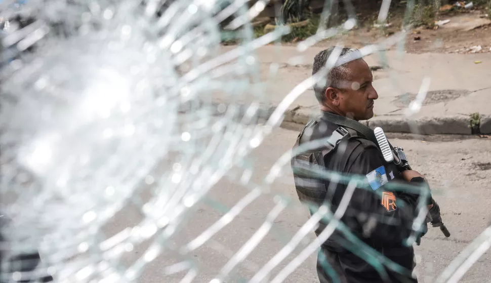 epaselect epa11813572 A police officer holds his weapon as seen through a broken window during a police operation in Rio de Janeiro, Brazil, 08 January 2025. Several people were killed during a police operation in a group of favelas in Rio de Janeiro that also targeted the facilities of the Oswaldo Cruz Foundation (Fiocruz), the main scientific research center in Brazil. EPA/ANDRE COELHO