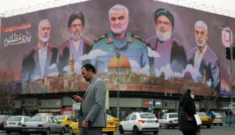 epa11808827 Iranians walk past a billboard with the pictures of late Iranian Islamic Revolutionary Guard Corps (IRGC) Quds Force commander Qasem Soleimani (C), late Hamas leaders Ismail Haniyeh (L) and Yahya Sinwar (R), and late Hezbollah leader Hasan Nasrallah (2-R), and the head of Hezbollah's executive council Hashem Safieddine (2-L), and a sentence reading in Persian 'God wrote our duty, help to the oppressed' hanging at the Enghelab square in Tehran, Iran, 06 January 2025. EPA/ABEDIN TAHERKENAREH