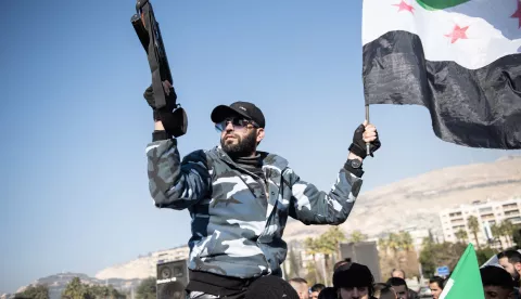 epa11803641 A former prisoner of Sednaya Prison holds a weapon and the Syrian opposition flag during a demonstration to celebrate their freedom and demand their right to hold their jailers accountable, at Umayyad Square in Damascus, Syria, 03 January 2025. EPA/HASAN BELAL