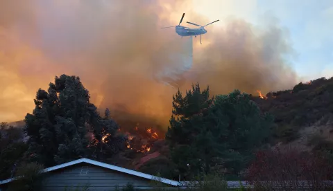 epaselect epa11819202 A helicopter does a water drop over a home during the Palisades wildfire in Los Angeles, California, USA, 11 January 2025. Thousands of firefighting and emergency personnel are involved in response efforts, as multiple wildfires are continuing to burn across thousands of acres in Southern California, destroying thousands of homes and forcing people to evacuate areas throughout the Los Angeles area. EPA/ALLISON DINNER