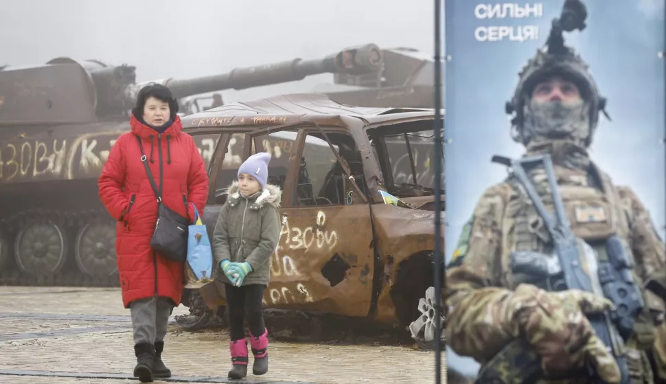 epa11766514 A woman and a child walk past destroyed Russian military machinery and damaged Ukrainian civilian vehicles displayed near St. Mykhailivsky Cathedral in downtown Kyiv, Ukraine, 09 December 2024, amid the ongoing Russian invasion. EPA/SERGEY DOLZHENKO 71058