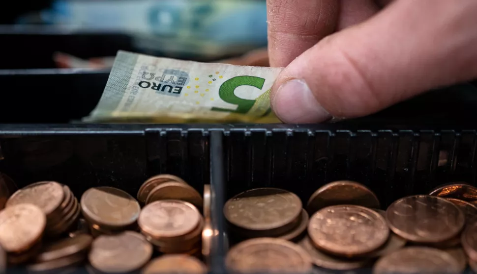 30 March 2022, Baden-Wuerttemberg, Stuttgart: An employee at a retail store takes a 5-euro bill from a checkout counter. Inflation, already high, has picked up further in the southwest. The inflation rate in March was 6.3 percent compared to the same month last year, according to the State Statistics Office in Stuttgart. Photo: Marijan Murat/dpa Photo: Marijan Murat/DPA