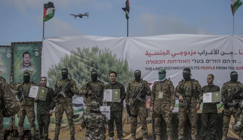epa11915384 Fighters from Hamas' Izz ad-Din al-Qassam Brigades pose with Israeli hostages (L-R) Eliya Cohen, Omer Shem Tov and Omer Wenkert before handing them over to the Red Cross in Al Nusairat refugee camp, central Gaza Strip, 22 February, 2025. Two further hostages were released earlier in the day in Rafah, southern Gaza Strip, in the final part of the first phase of the Israel-Hamas ceasefire deal. EPA/MOHAMMED SABER
