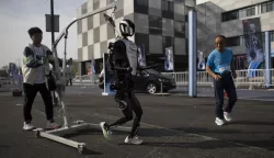 epa12036662 Zhang Xianghua (71), a runner who will take part in the race, joggs next to a humanoid robot ahead of a humans and robots race in Beijing, China, 17 April 2025. Beijing will host a half marathon on April 19, in which humans and robots will participate. EPA/ANDRES MARTINEZ CASARES