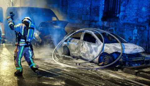 epa11800628 A firefighter works to extinguish burning vehicles during New Year's Eve celebrations in Brussels, Belgium, 01 January 2025. Each year, several cars are set on fire in Brussels on New Year's Eve night. EPA/OLIVIER MATTHYS