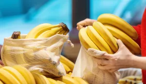 Woman picking bananas in a reusable bag in a store. Ecology and Earth Day thematicsbanane voće ilustracija freepik