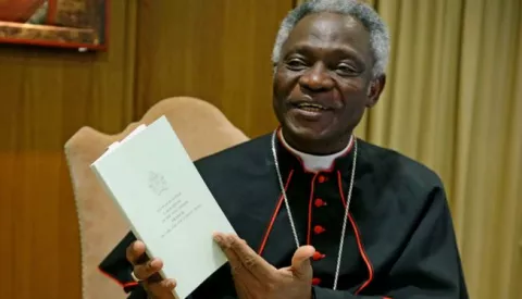 epa04806176 Cardinal Peter Kodwo Appiah Turkson holds a copy of Pope Francis's encyclical, a collection of principles to guide Catholic teaching, entitled 'Laudato Si' during its official presentation at the Sinod hall in the Vatican City, 18 June 2015. EPA/ALESSANDRO DI MEO