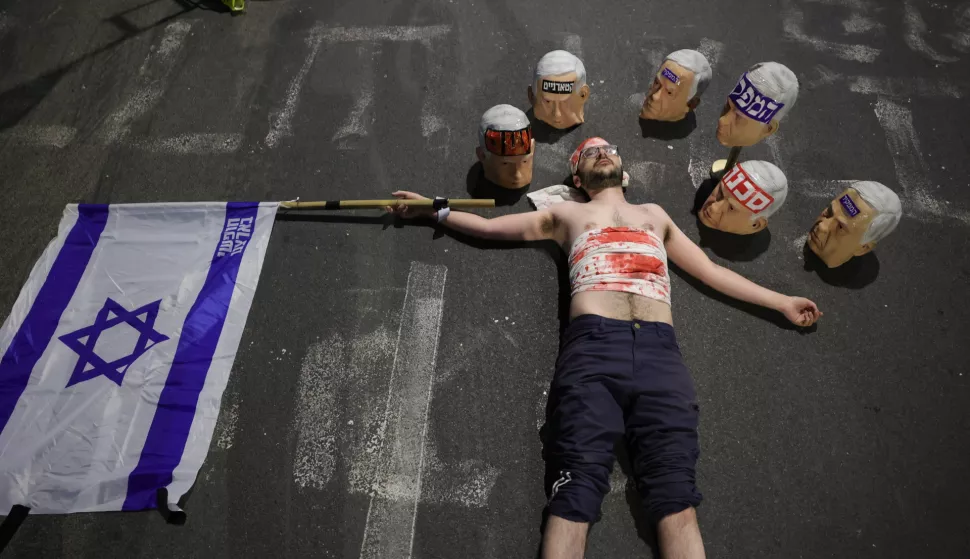 epa12057099 A demonstrators covered in fake blood lies on the street near masks depicting Israeli Prime Minister Benjamin Netanyahu and a national flag as the families of Israeli hostages held by Hamas in Gaza and their supporters take part in a protest calling for the completion of an hostage deal between Israel and Hamas, outside the the Kirya military headquarters in Tel Aviv, Israel, 26 April 2025. According to Israel's military, around 59 Israeli hostages remain in captivity in the Gaza Strip, including the bodies of at least 35 confirmed dead. EPA/ABIR SULTAN