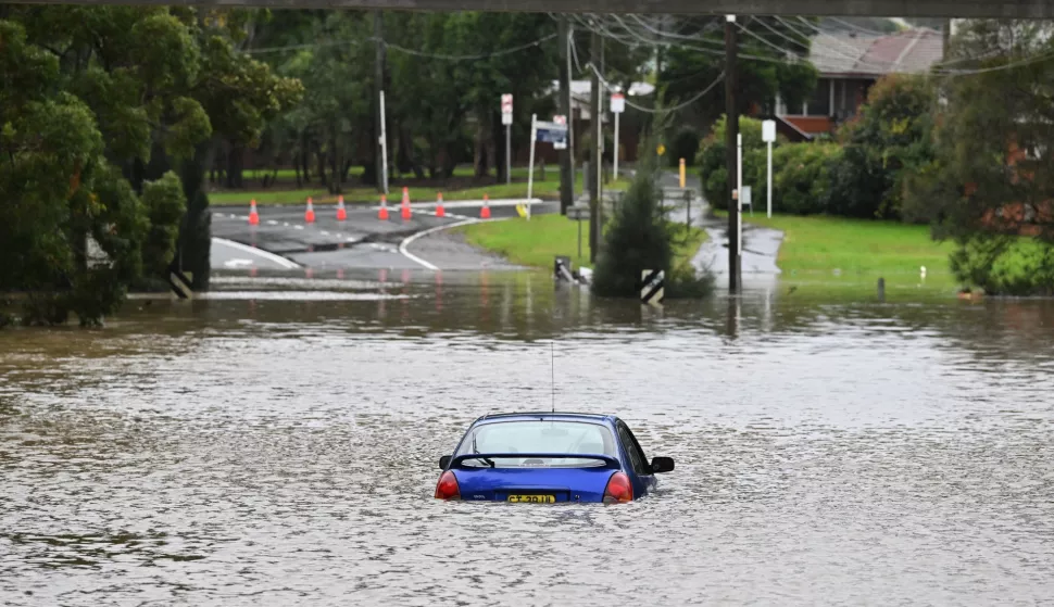 epa10049219 A car is seen abandoned in floodwaters in Lansvale in Western Sydney, Australia, 03 July 2022. Torrential rain and damaging winds hit New South Wales state forcing the evacuation of thousands of residents. New South Wales emergency services minister Steph Cooke warned citizens that the floods could be more dangerous than last year's. EPA/MICK TSIKAS AUSTRALIA AND NEW ZEALAND OUT