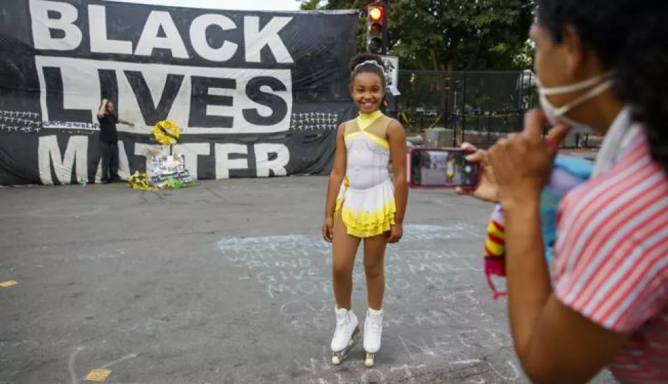 epa08476930 A mother photographs her daughter skating in front of a huge Black Lives Matter banner at Lafayette Park in Washington, DC, USA, 10 June 2020. Work crews have started to remove the fencing that was erected around the White House grounds and Lafayette Square during the protests over the death of George Floyd in police custody. EPA/SHAWN THEW
