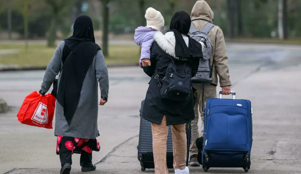 dpatop - 13 March 2025, Brandenburg, Eisenh?ttenstadt: Migrants leave the premises of Brandenburg's Central Immigration Office (ZABH) with luggage. Brandenburg is taking a new approach to speeding up the return of asylum seekers to Poland. A new so-called "Dublin Center" for the faster return of asylum seekers to other EU states is starting work. The aim is to speed up the organization of transfers to Poland. This involves so-called Dublin cases, i.e. people who have to go through their asylum procedure in another EU country. Photo: Patrick Pleul/dpa Photo: Patrick Pleul/DPA