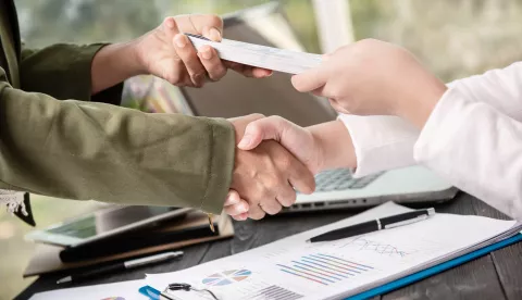 Business people shaking hands, finishing up meeting. businessman giving money to his partner while making contract - bribery and corruption concepts.banka novac kredit ilustracija freepik