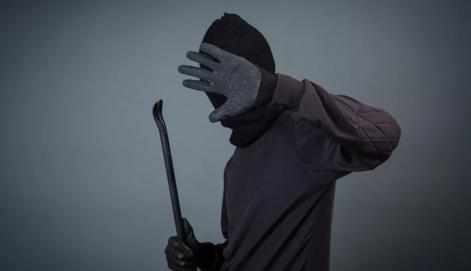 Black criminals wore a head yarn on a gray background.  imali su pajser, i dva ključa s kojima su nasilno otvarali zaključana vrata. Na glavu su stavili kapuljaču, a na ruke građevinske rukavice. lopov provalnik pajser krađa kriminal ilustracijafreepik