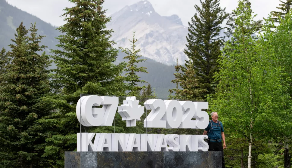 epa12175997 A tourist poses for a picture at a sign advertising the G7 Summit at the International Media Centre on the grounds of the Banff Centre for Arts and Creativity in Banff, Canada, 14 June 2025. World leaders are expected to gather in nearby Kananaskis, Alberta, from 15 to 17 June. EPA/SPENCER COLBY