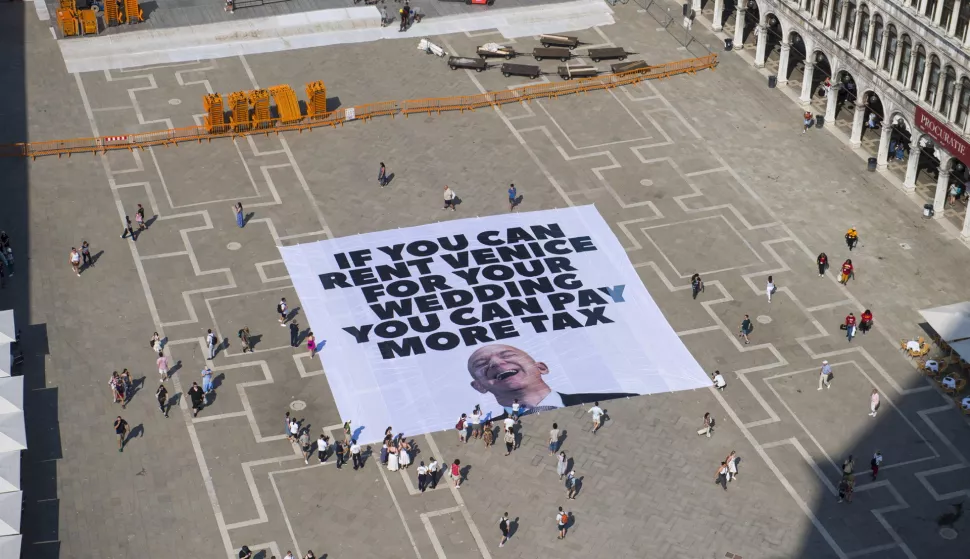 epa12192418 A handout photo made available by Greenpeace press office shows activists of the environmental group Greenpeace unfolding a giant banner with the image of US businessman and Amazon founder Jeff Bezos, and a slogan reading 'If you can rent Venice for your wedding you can pay more tax' at St Mark's Square in Venice, Italy, 23 June 2025. Venice will host the wedding of Jeff Bezos and his fiancee journalist Lauren Sanchez in June 2025. EPA/GREENPEACE PRESS OFFICE HANDOUT HANDOUT EDITORIAL USE ONLY/NO SALES