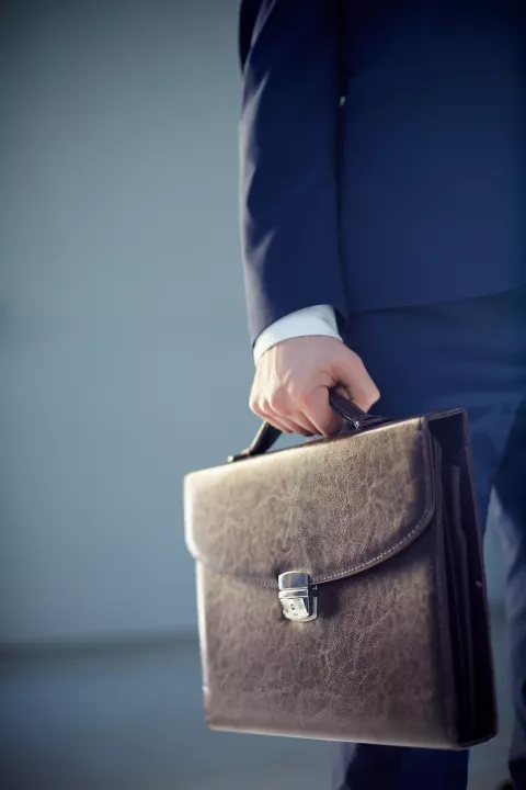 Vertical cropped image of a businessperson carrying a leather briefcase isolated on grey posao gospodarstvo ilustracija aktovka banka kredit pdv bdp gdp pregovori financiranje financije računovostvo freepik