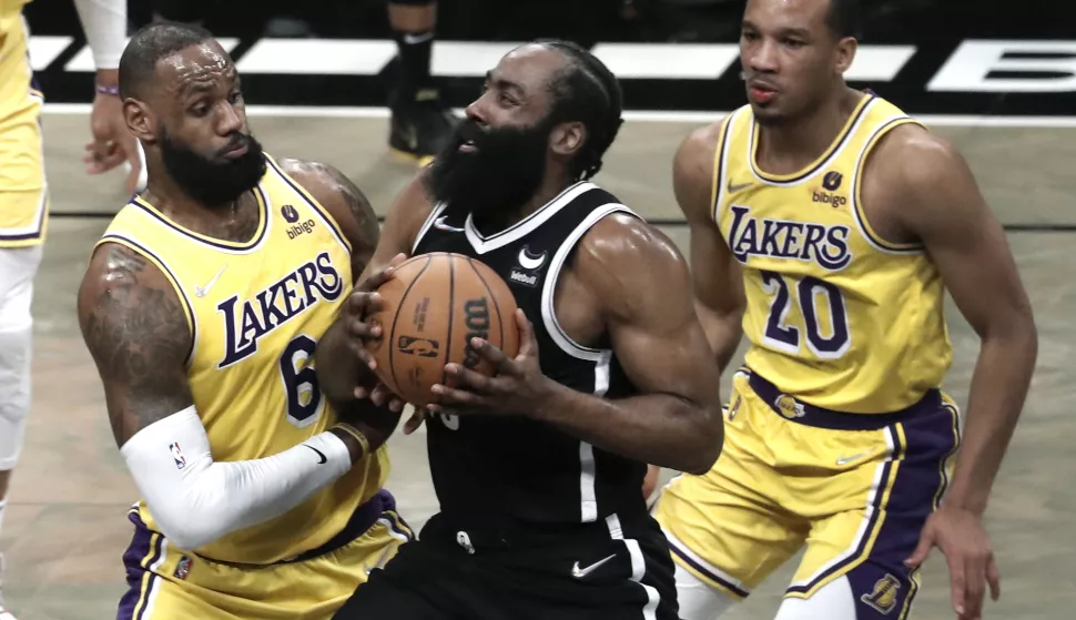 epa09709538 Brooklyn Nets guard James Harden (C) is defended by Los Angeles Lakers forward Lebron James (L) during the first half of the NBA basketball game between the Brooklyn Nets and the Los Angeles Lakers at Barclays Center in Brooklyn, New York, USA, 25 January 2022. EPA/Peter Foley SHUTTERSTOCK OUT