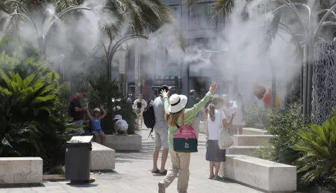 epa12204409 Tourists cool off under a cloud of mist at the Plaza de la Reina during a heat wave in Valencia, Spain, 29 June 2025. Spain is undergoing its first summer heat wave due to a broad anticyclone originating from the interior of the African continent which is expected to last until 01 July, according to the State Meteorological Agency (AEMET). EPA/MANUEL BRUQUE