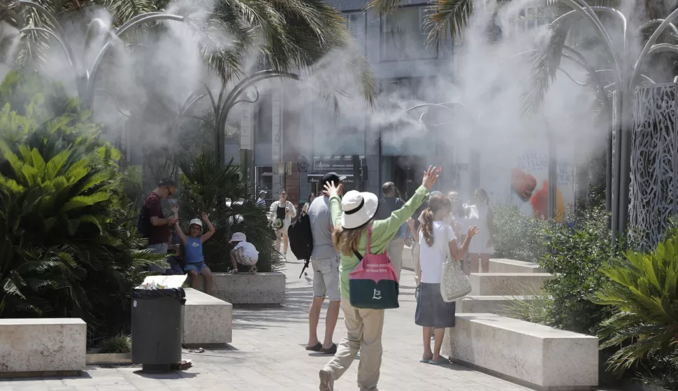 epa12204409 Tourists cool off under a cloud of mist at the Plaza de la Reina during a heat wave in Valencia, Spain, 29 June 2025. Spain is undergoing its first summer heat wave due to a broad anticyclone originating from the interior of the African continent which is expected to last until 01 July, according to the State Meteorological Agency (AEMET). EPA/MANUEL BRUQUE