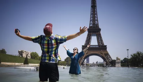 epa12208719 People cool off with water from Varsovie fountain by the Eiffel Tower during a heatwave in Paris, France, 01 July 2025. The hottest day of this heatwave on 01 July 2025, will register temperatures peaking into 40-41 degrees Celsius, in several departments, according to Meteo France. EPA/YOAN VALAT