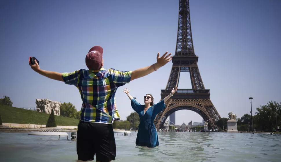 epa12208719 People cool off with water from Varsovie fountain by the Eiffel Tower during a heatwave in Paris, France, 01 July 2025. The hottest day of this heatwave on 01 July 2025, will register temperatures peaking into 40-41 degrees Celsius, in several departments, according to Meteo France. EPA/YOAN VALAT