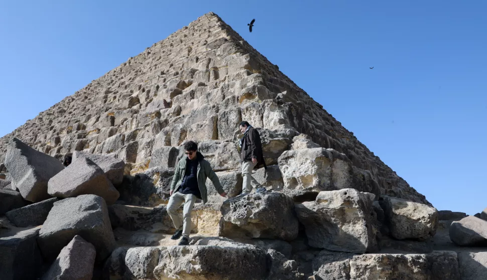 epa11118019 Tourists climb the stones at the base of the Pyramid of Menkaure, at the Giza Pyramids Necropolis, in Giza, Egypt, 01 February 2024. An Egyptian-Japanese joint project led by secretary-general of the Supreme Council of Antiquities Mostafa Waziri is to renovate the Pyramid of Menkaure, which dates back to the 26th century BC and is the smallest of the three main pyramids of the Giza pyramid complex. EPA/KHALED ELFIQI