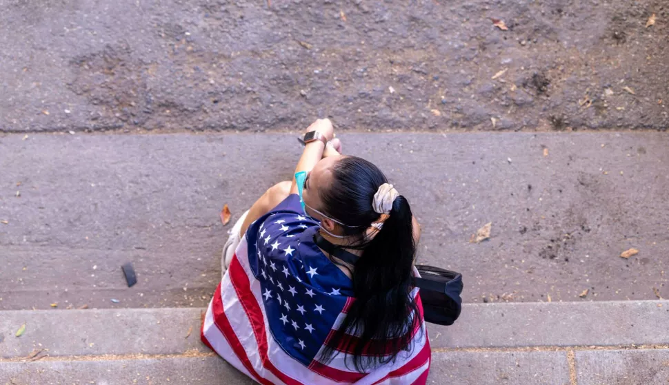 A woman draped in an American flag sits on the steps during an anti-ICE protest in downtown Los Angeles, California, on June 8, 2025. The protest erupted after a wave of federal immigration raids began on June 7, with National Guard troops deployed to the city despite objections from local officials. Demonstrators called for an end to deportations and the dismantling of ICE. Photo by Sahab Zaribaf/Middle East Images/ABACAPRESS.COM Photo: Middle East Images/ABACA/ABACA