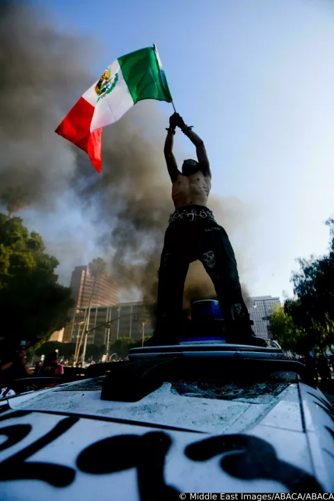A protester waves the Mexican flag atop a Waymo vehicle during an anti-ICE protest in downtown Los Angeles, California, on June 8, 2025. The protest erupted after a wave of federal immigration raids began on June 7, with National Guard troops deployed to the city despite objections from local officials. Demonstrators called for an end to deportations and the dismantling of ICE. Photo by Benjamin Hanson/Middle East Images/ABACAPRESS.COM Photo: Middle East Images/ABACA/ABACA