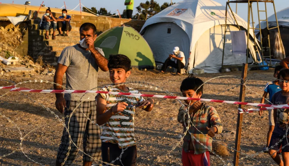 epa08682489 Adults and minors refugees and migrants stand behind razor wire at Kara Tepe camp on Lesbos island, Greece, 19 September 2020. Following the catastrophic fires at Moria on September 8 and 9, a total of 9,000 people were rehoused at the hotspot of Kara Tepe, south of Mytilini. All of them have been identified and their asylum applications are in process. Of them, 213 were found positive to the novel coronavirus and have been quarantined at separate quarters in the hotspot. EPA/VANGELIS PAPANTONIS