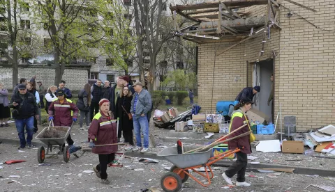 epa12038475 People stand at the site of a rocket attack near a high-rise building in a residential area in Kharkiv, Ukraine, 18 April 2025, amid the ongoing Russian invasion. At least one person died, and more than 80 others were injured, including six children, according to the State Emergency Service. EPA/SERGEY KOZLOV