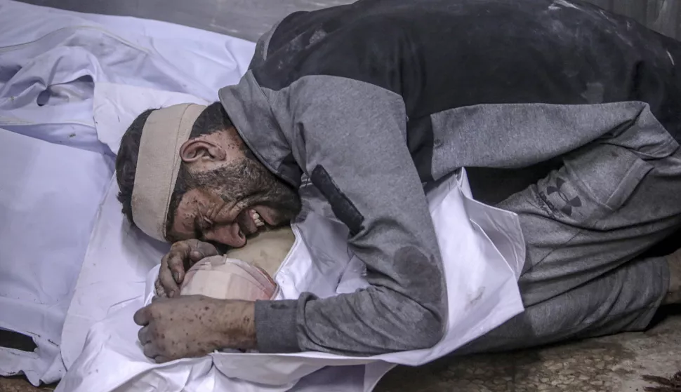epa12238714 A Palestinian man mourns over the body of his dead child at the Al-Shifa hospital after an Israeli air strike in Gaza City, 15 July 2025. The Palestinian Ministry of Health in Gaza said that more than 30 Palestinians were killed following Israeli air strike over night and early in the day. EPA/MOHAMMED SABER