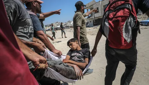 epa12249920 Palestinians carry the body of a boy after he was shot dead at a food distribution point near Zikim, northern Gaza Strip, 20 July 2025. According to the Palestinian Ministry of Health in Gaza, at least 67 people were killed while trying to receive humanitarian aid in the Zikim area. EPA/MOHAMMED SABER