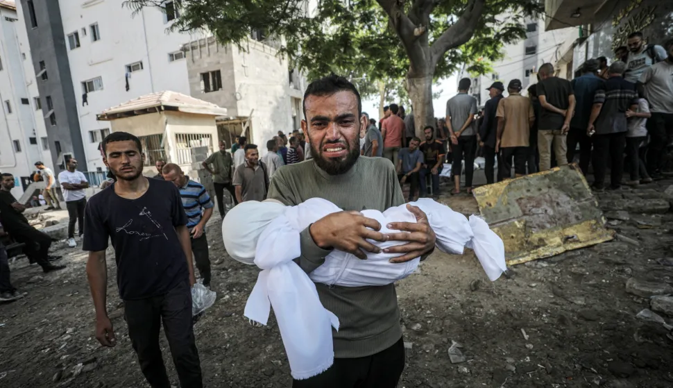 epa12255235 A father carries the shrouded body of his child at the Al-Shifa in Gaza City, 23 July 2025. According to the Palestinian Ministry of Health in Gaza, more than 36 Palestinians were killed, tem of them from the Mushtaha family, following Israeli airstrikes last night and early today. EPA/MOHAMMED SABER