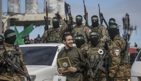 epa11915305 Fighters from Hamas' Izz ad-Din al-Qassam Brigades escort Israeli hostage Omer Shem Tov before handing him over to the Red Cross in Al Nusairat refugee camp, central Gaza Strip, 22 February, 2025. Two further hostages were released earlier in the day in Rafah, southern Gaza Strip, in the final part of the first phase of the Israel-Hamas ceasefire deal. EPA/MOHAMMED SABER