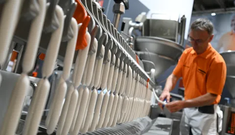 13 May 2022, Hessen, Frankfurt/Main: Markus Schließer, development engineer, stands at the booth of Handtmann-Maschinenfabrik from Biberach at a ConProLink system from which sausages are hanging on which a vegan casing has been injected. The Frankfurt meat industry trade show IFFA (May 14-19) is increasingly focusing on plant-based proteins. More than 200 of the 860 exhibitors will inform visitors about technologies and solutions on meat alternatives. Photo: Arne Dedert/dpa Photo: Arne Dedert/DPA