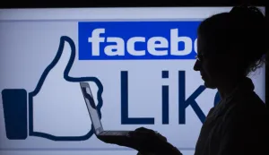 ILLUSTRATION - A woman works on her computer in front of the lighted facebook-sign in Schwerin, Germany, 04 April 2013. In Germany alone the social network counts over 25 million users. Photo: Jens Buettner/DPA/PIXSELL
