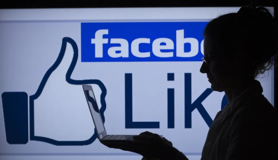 ILLUSTRATION - A woman works on her computer in front of the lighted facebook-sign in Schwerin, Germany, 04 April 2013. In Germany alone the social network counts over 25 million users. Photo: Jens Buettner/DPA/PIXSELL