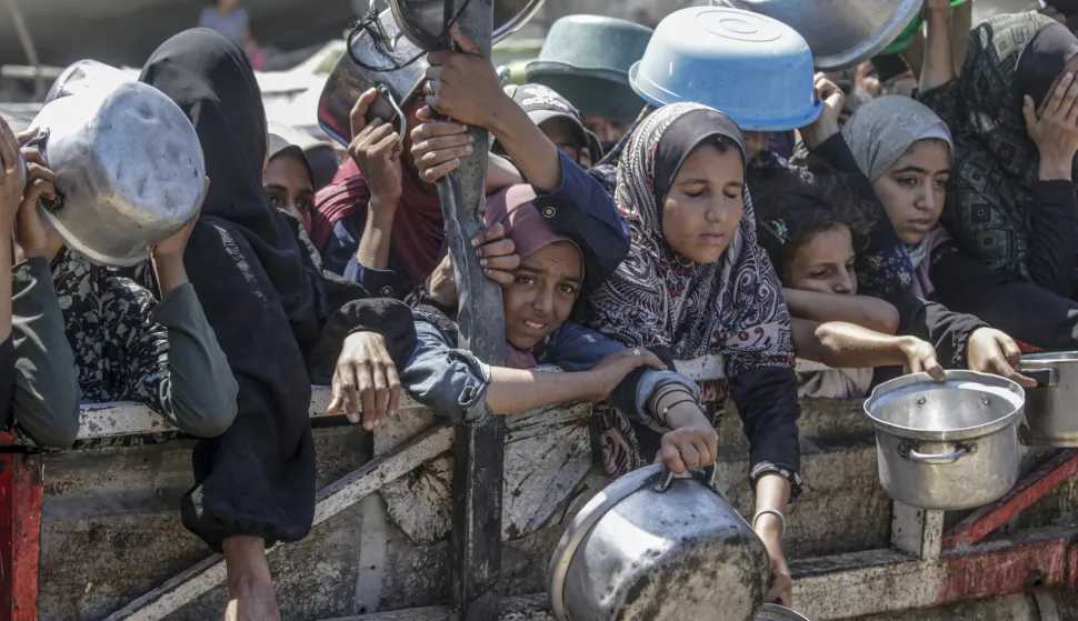 epa12282743 Internally displaced Palestinians, including children, hold pots as they gather to receive food from a charity kitchen, in Gaza City, Gaza Strip, 04 August 2025. Humanitarian organizations have warned of an imminent food catastrophe for thousands of children, a crisis caused by severe food insecurity, a decline in health services, and ongoing restrictions on humanitarian aid and essential supplies. EPA/MOHAMMED SABER