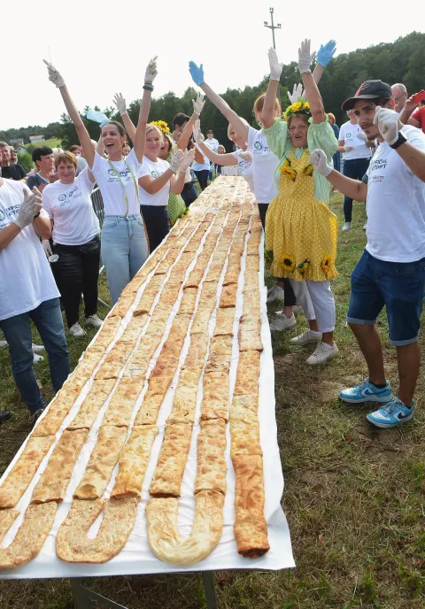 Ozalj, 06.09. 2025. - Jaškovo u općini Ozalj danas se po drugi puta upisalo u Guinnessovu knjigu svjetskih rekorda, složenom štrudlom od jabuke ukupne dužine 3.136 metara, koja je sastavljena od 8.940 komada štrudle. Sve je to bilo postavljeno na stolove u obliku dvostruke šesterokrake zvijezde, tlocrta tvrđave na kojoj se razvio Karlovac. Rekord je verificirala Guinnesova sutkinja Paulina Sapinska. Na fotografiji završetak rekordne štrudle od jabuka u Jaškovu. foto HINA/ Mladen VOLARIĆ/ mv