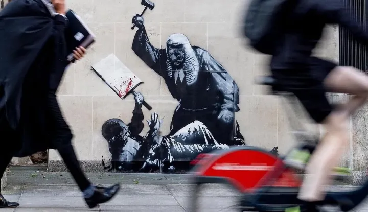 LONDON, 8. rujna 2025. (Hina/Reuters) - Britanski ulični umjetnik Bansky naslikao je mural na londonskom Visokom sudu koji prikazuje suca koji tuče prosvjednika, &scaron;to je vjerojatno reakcija na uhićenje stotina prosvjednika na skupu potpore zabranjenoj skupini Akcija za Palestinu.