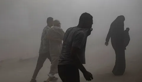 epa12380197 People walk as smoke and dust fill the air after the Al-Ghafari residential tower was hit by an Israeli airstrike in Gaza City, 15 September 2025. More than 64,900 Palestinians have been killed in the Gaza Strip since October 2023, according to the Palestinian Ministry of Health. EPA/HAITHAM IMAD