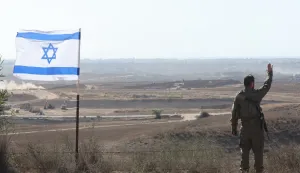epa12272998 An Israeli soldier gestures next to an Israeli flag at an area near the Israel-Gaza border in southern Israel, 30 July 2025. EPA/ABIR SULTAN
