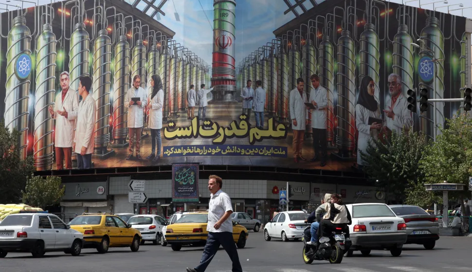 epa12342275 An Iranian man crosses a road near a billboard displaying a picture of nuclear centrifuges and a sentence reading in Persian 'Science is the power, and the Iranian nation will not abandon its religion and knowledge' at the Enghelab square in Tehran, Iran, 01 September 2025. EPA/ABEDIN TAHERKENAREH