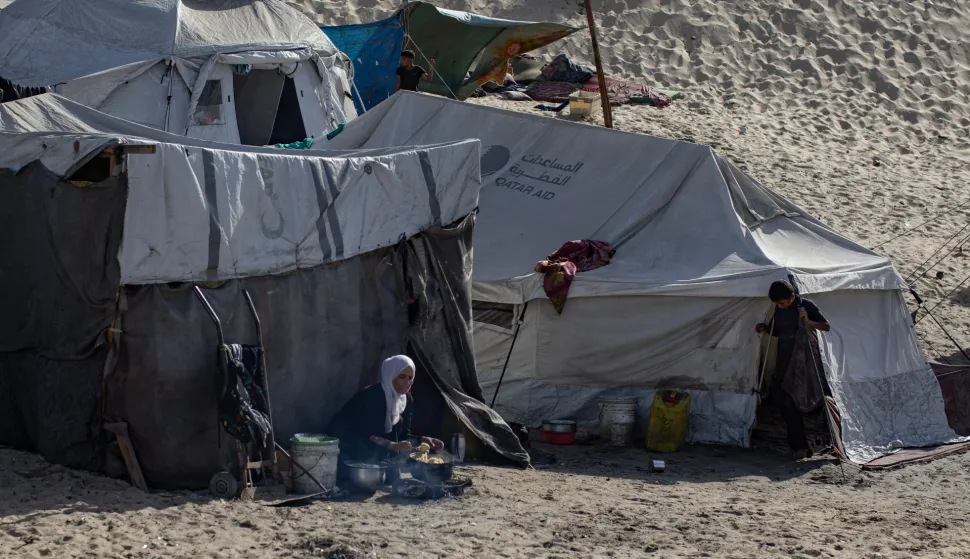 epa12415109 ​A woman prepares a meal in front of a tent set up by displaced Palestinians from the northern Gaza Strip in the Al-Mawasi area of Khan Younis, in the southern Gaza Strip, 25 September 2025. According to the UN, around 90 per cent of the population or 1.9 million people in Gaza, have been displaced since the start of the conflict. EPA/HAITHAM IMAD