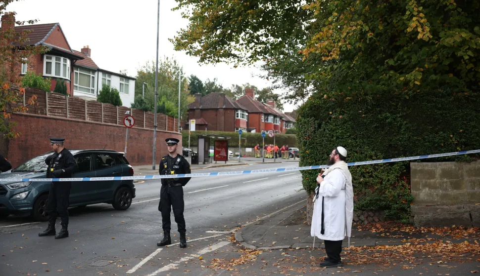 epa12423583 A member of the a Jewish Community holds a Torah at a police cordon in Manchester, Britain, 02 October 2025. Two people have died after a car and stabbing attack at a synagogue in Manchester, with the suspect shot by police. EPA/ADAM VAUGHAN
