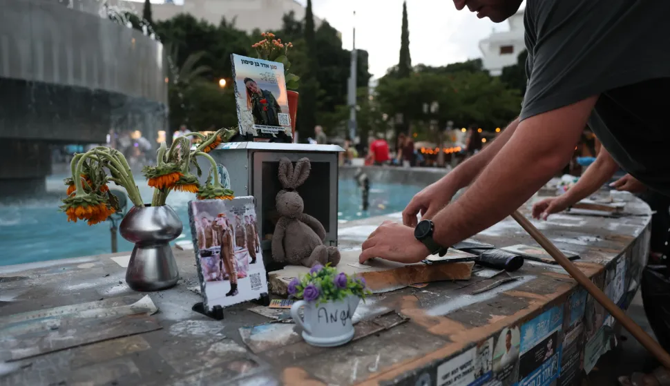 epa12433263 People cleaning pictures and memorials of Israeli victims of the October 7th attack at the fountain of Dizengoff Square in Tel Aviv, Israel, 05 October 2025. Two years after the public square became a memorial site, people are cleaning it up and will replace the items on 07 October as part of the Hamas attack's two-year anniversary. EPA/ABIR SULTAN