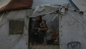 epaselect epa12438128 An internally displaced Palestinian mother carrying her child in their tent at the Gaza port during an Israeli military operation in Gaza City, Gaza Strip, 07 October 2025. According to the UN around 90 percent of the population or 1.9 million people in Gaza have been displaced since the start of the conflict. More than 67,000 Palestinians have been killed in the Gaza Strip since October 2023, according to the Palestinian Ministry of Health, and about 1,200 Israelis have been killed since the launch of an Israeli military campaign in response to a cross-border attack by Hamas on 07 October 2023. EPA/MOHAMMED SABER