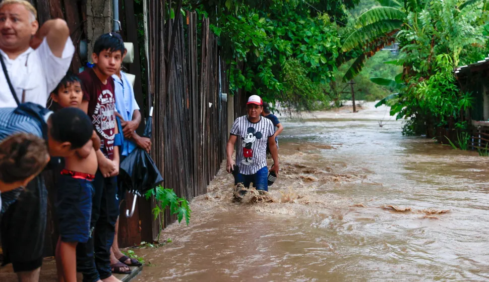 epa10910579 People walk in a flooded area due to tropical storm Max in the municipality of Tecpan de Galeana, Guerrero, Mexico 09 October 2023. Tropical Storm Max made landfall in Guerrero state, southern Mexico, on October 9, expected to cause intense rains with occasional torrential rains, gusts of wind and waves on the coasts, according to the National Meteorological Service (SMN). EPA/David Guzman