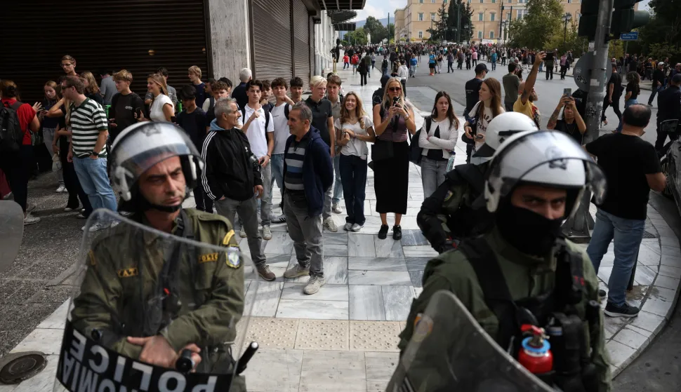 epa12452775 Tourists are pictured along with riot police officers during a demonstration of a 24-hour nationwide general strike, in Athens, Greece, 14 October 2025. The Athens Labor Center (EKA) and the Civil Servants' Confederation (ADEDY) are staging a 24-hour general strike in response to the provisions of the new labor bill being debated in Parliament, which establishes the '13-hour workday. EPA/GEORGE VITSARAS